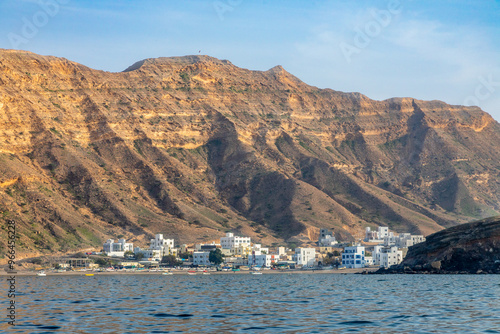 Al-Bustan village white houses on the shore view from the sea bay with mountains in the background, Muscat, sultanate Oman photo