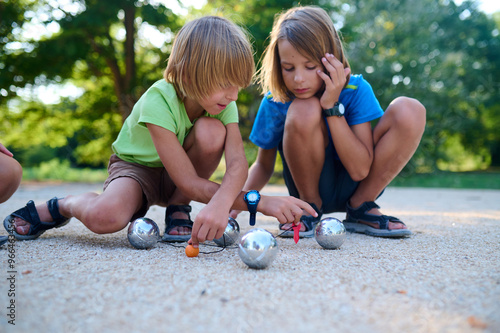 Cuadro en lienzo Two children measure the distance between petanque balls and the target ball during a game