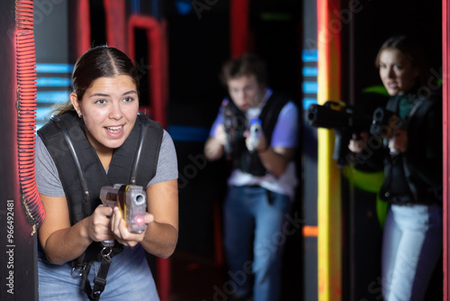 Young lady having fun playing lasertag in arena photo