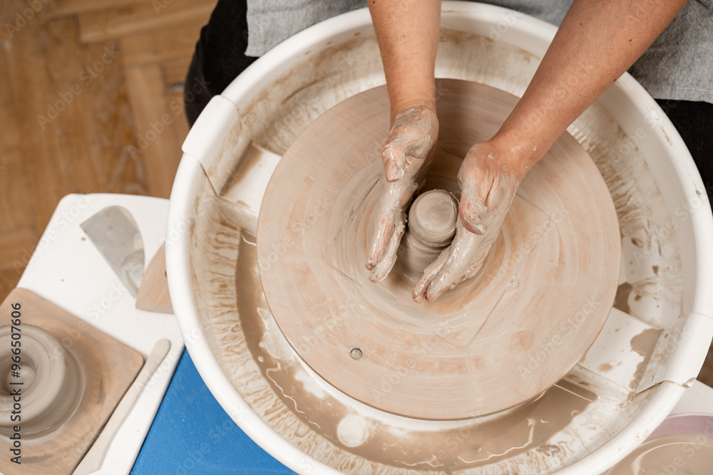Fototapeta premium Girl is making a bowl on a pottery wheel with your own hands. Forming the proper size and shape of pottery with increasing speed of a pottery wheel.