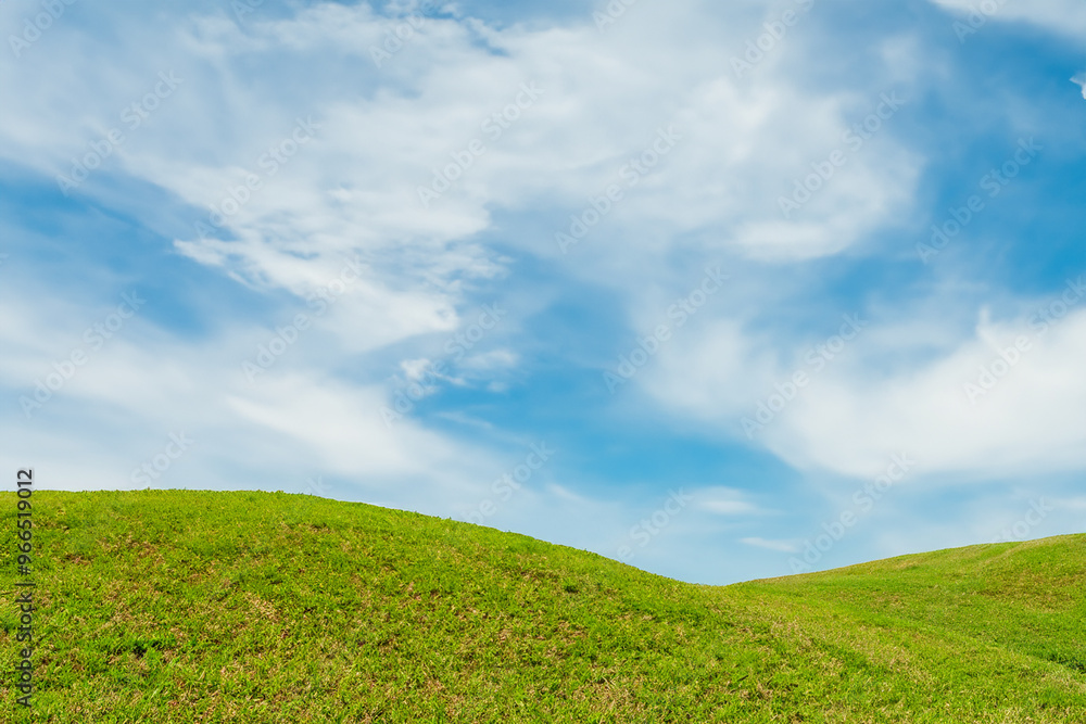 A bright blue sky with white clouds over a rolling green hill. A bright blue sky with white clouds over a rolling green hill.