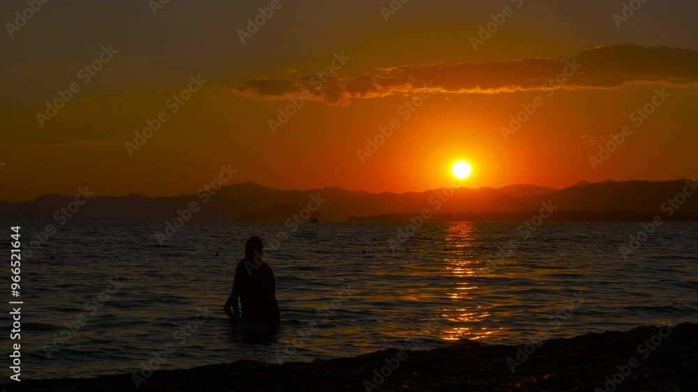 Travelers swim in sea after dusk. A family travelers admire the sunset in the sea waves during summer holidays. Travelers swim in sea after dusk. A family travelers admire the sunset in the sea waves during summer holidays.