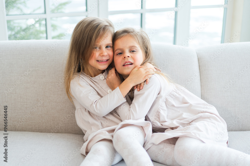 Happy family sisterly love. Two funny little twin sisters girls hugging with love care playing together at home indoors. Happy children lifestyle. Identical twin girls hugs. Girls friendship and youth Happy family sisterly love. Two funny little twin sisters girls hugging with love care playing together at home indoors. Happy children lifestyle. Identical twin girls hugs. Girls friendship and youth