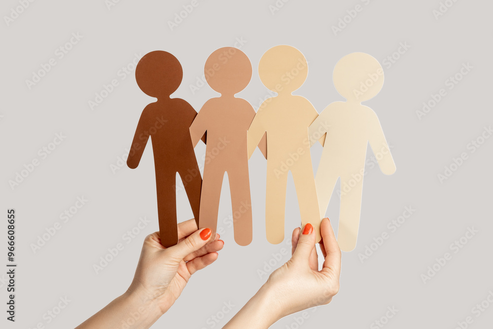 Closeup of woman hand showing paper symbols of multicultural people, racism, partnership. Indoor studio shot isolated on gray background. Closeup of woman hand showing paper symbols of multicultural people, racism, partnership. Indoor studio shot isolated on gray background.