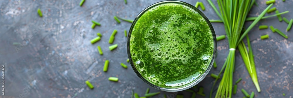Aerial view of a glass containing freshly made barley grass juice, adorned with blades and powder. Aerial view of a glass containing freshly made barley grass juice, adorned with blades and powder.