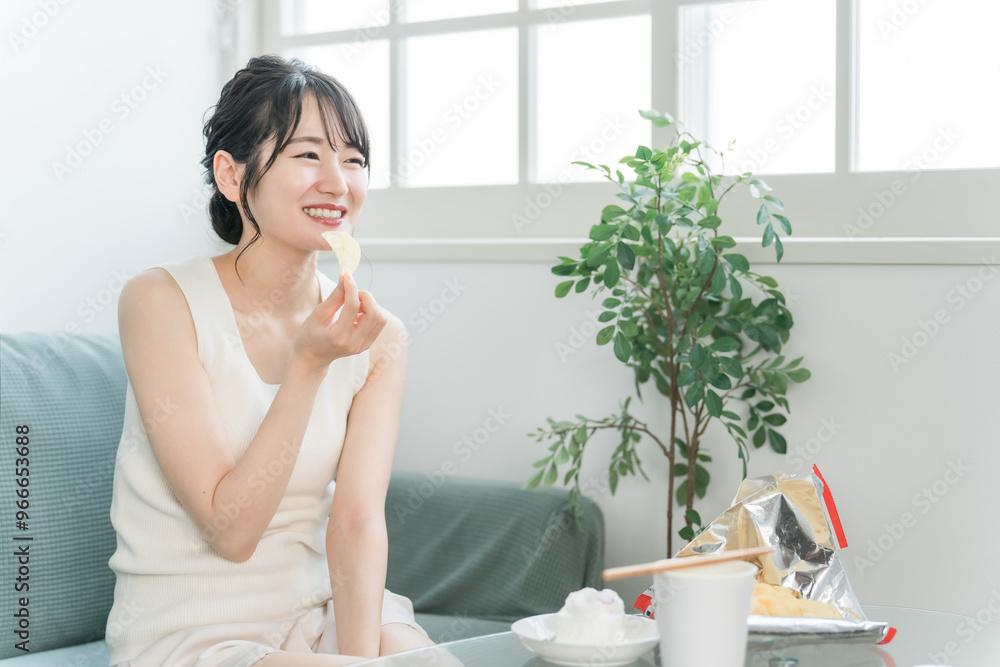 自宅のソファでポテトチップスを食べる若いアジア人女性(暴飲暴食・間食・高カロリー)
自宅のソファでポテトチップスを食べる若いアジア人女性(暴飲暴食・間食・高カロリー)