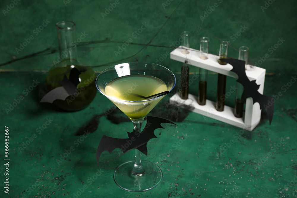 Φωτογραφία Glass of delicious cocktail for Halloween with test tubes and paper bats on gree