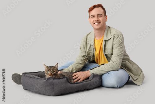 Young man with cute cat lyi...