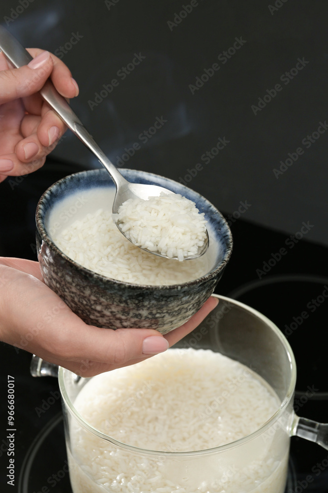 Woman taking boiled rice from pot into bowl, closeup Woman taking boiled rice from pot into bowl, closeup