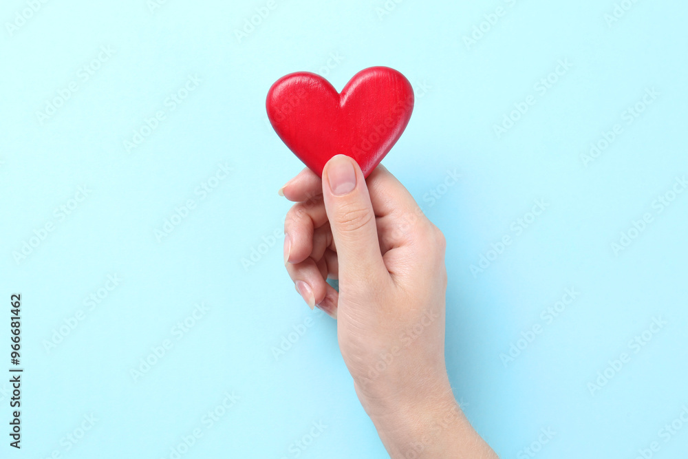 Woman with red heart on light blue background, closeup Woman with red heart on light blue background, closeup