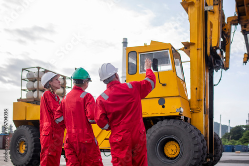 Engineer or worker are standing forklift or truck vehicle are holding detail and appear to be discussing or reviewing documents, likely related to inspect about factory and industry environment. photo