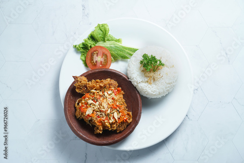 Ayam geprek is a typical Indonesian dish of fried chicken with flour that is mashed or mashed with plow chili sauce. photo