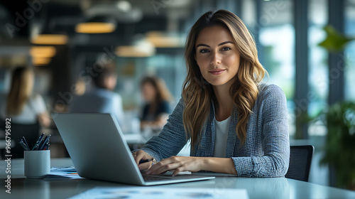 A woman is sitting at a desk with a laptop in front of her