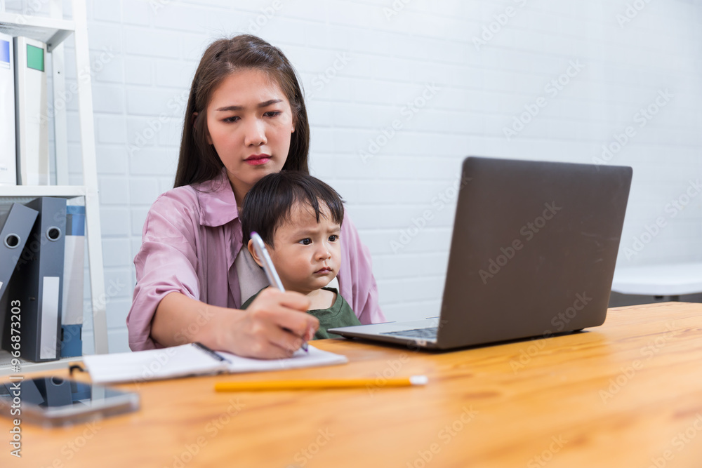 Asian businesswoman working in modern office while looking after child,teaching working and being a family care motherhood raising her kid while working with computer laptop technology Asian businesswoman working in modern office while looking after child,teaching working and being a family care motherhood raising her kid while working with computer laptop technology
