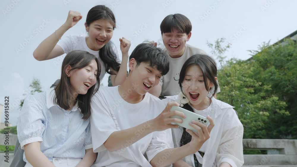  Happy young group of friends using phone and smiling together outdoor. 