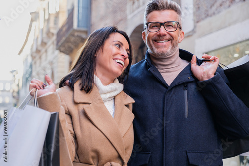 Happy couple strolls through a busy city street in Italy, carrying shopping bags and enjoying time together photo