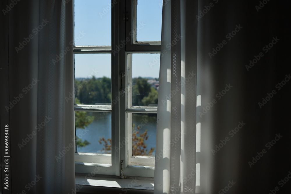 The blurred view of the river through the charming old window with curtains nearby. The blurred view of the river through the charming old window with curtains nearby.