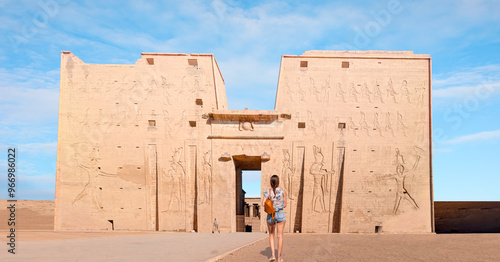 A beautiful young girl in shorts is standing watching and historical artifacts - Ancient Egyptian relics in the Temple of Horus - Edfu, Egypt. photo