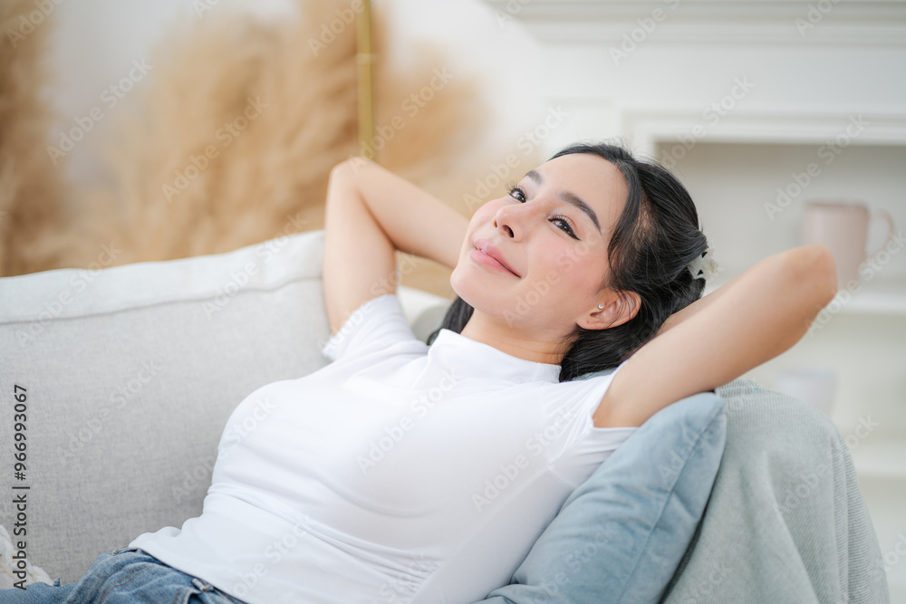 Copy space shot of young woman reclining on sofa with hands behind head and relaxing happily
Copy space shot of young woman reclining on sofa with hands behind head and relaxing happily