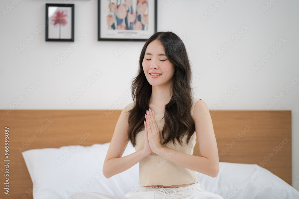 Asian woman doing a yoga pose with hands clasped on the bed Asian woman doing a yoga pose with hands clasped on the bed