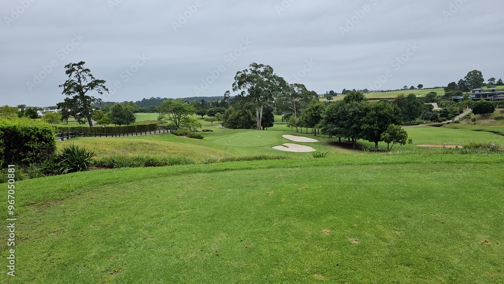 Lush green golf course landscape with sand traps and trees in the distance Lush green golf course landscape with sand traps and trees in the distance