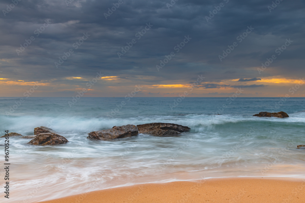 Sunrise at the seaside with rocks and beautiful diffused light by the rain clouds Sunrise at the seaside with rocks and beautiful diffused light by the rain clouds