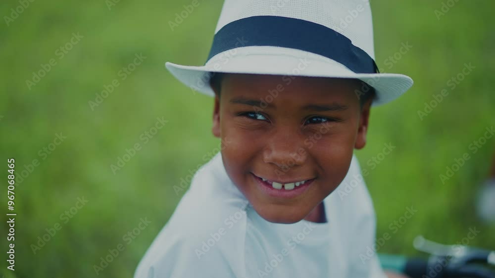 Young boy enjoying a sunny day outdoors in a white hat playing happily in the grass Young boy enjoying a sunny day outdoors in a white hat playing happily in the grass