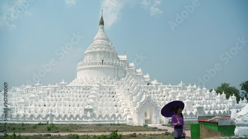 Pretty woman in treaditional suite holding violet paper umbrella travel and make a merit at Hsinbyume Pagoda in Mingun Mandaley, Myanmar. photo