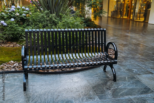 Obraz na płótnie A wrought iron bench is placed in shopping mall for people to sit and rest. w salonie