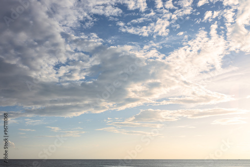 Darker dramatic clouds and sunlight beams at blue sky, capture from seaside