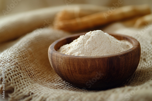 Ashwagandha powder in a wooden bowl standing on a brown canvas cloth with ashwagandha roots