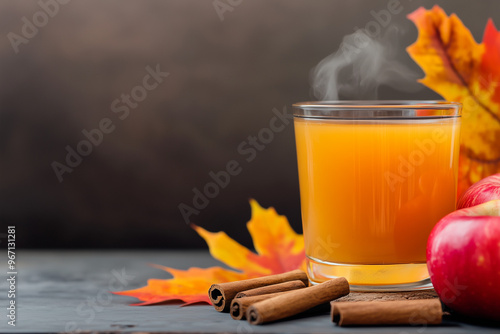 A glass of cinnamon apple cider served in a cozy autumn setting, with fall leaves and apples as decorations,  concept of seasonal drinks, autumn and cold time and traditional cousine photo