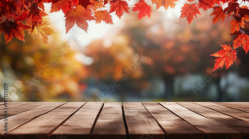 An empty wooden tabletop is set against a blurred backdrop of autumn trees with vibrant red leaves. This background creates a warm and inviting atmosphere, ideal for displaying or montaging your produ