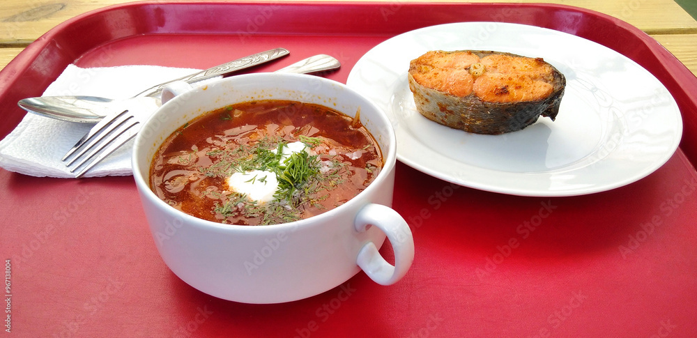 Borscht and a piece of fried fish on a red tray. Borscht and a piece of fried fish on a red tray.