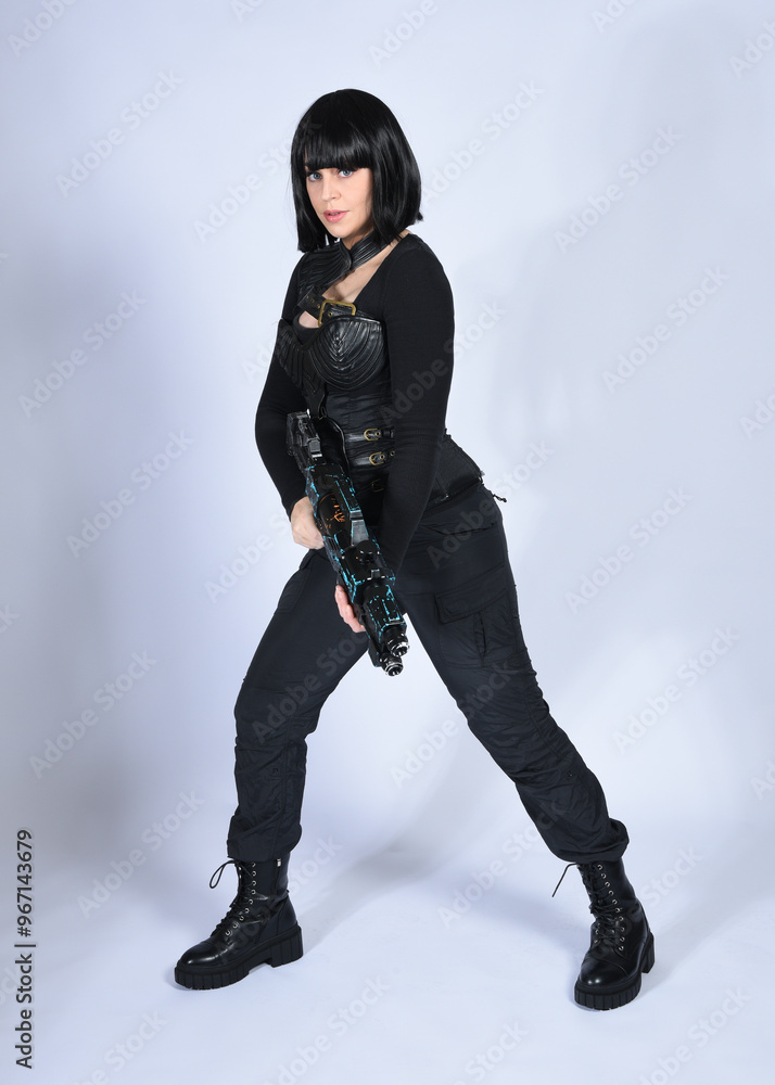Full length portrait of beautiful black female model with short black hair wearing sci fi futuristic dystopian leather bodysuit costume. Standing pose holding gun weapon, isolated white studio backgro Full length portrait of beautiful black female model with short black hair wearing sci fi futuristic dystopian leather bodysuit costume. Standing pose holding gun weapon, isolated white studio backgro