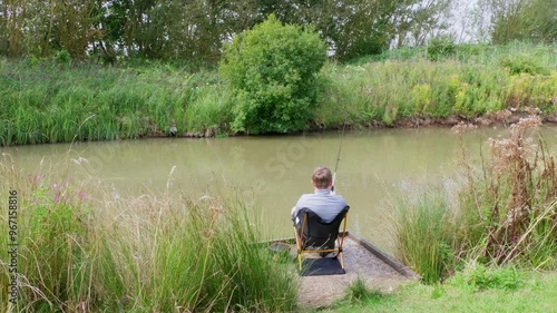 Young boys, boy fishing along the riverbank, Summer days angling by the river lake. Sitting peacefully and enjoying the lazy day photo