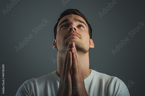 Young Man in White T-shirt Gazing Upwards with Hands in Prayer Pose