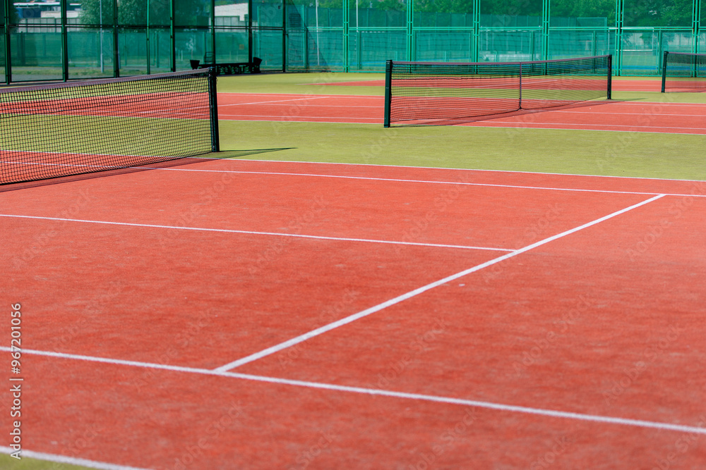 Fototapeta premium The tennis court is empty with a net and a green fence.
