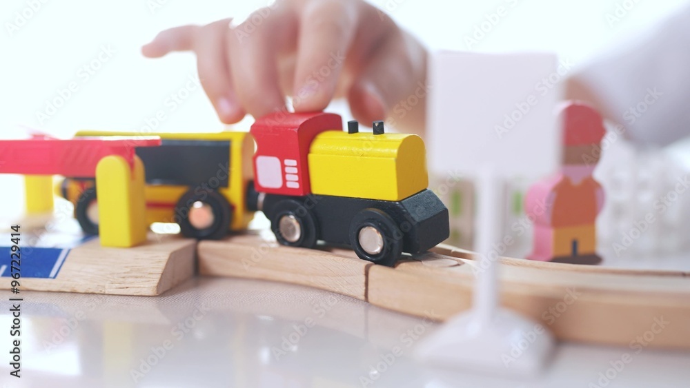 Children play with a toy train in kindergarten. Child childhood fun concept. Train with toy is traveling along railway. Children play with toys and trains on the railway in kindergarten lifestyle. Children play with a toy train in kindergarten. Child childhood fun concept. Train with toy is traveling along railway. Children play with toys and trains on the railway in kindergarten lifestyle.