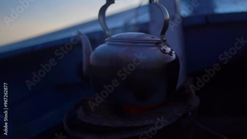 Kettle over the fire. An old vintage smoked teapot is boiling water over boiling metal  kettle on an in the morning, steam coming out, breakfast tea time, boiling water. photo