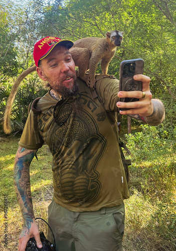 Andasibe, Madagascar - May 27, 2024: Tourist in Madagascar interacting with lemur while taking a selfie in lush green surroundings photo