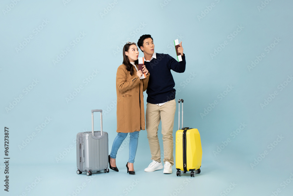 Winter travel portrait collection of amazed Asian couple looking up at copy space in studio blue color isolated background Winter travel portrait collection of amazed Asian couple looking up at copy space in studio blue color isolated background