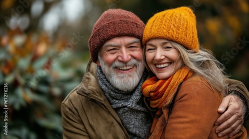 A man and a woman are smiling and hugging each other. They are wearing hats and scarves