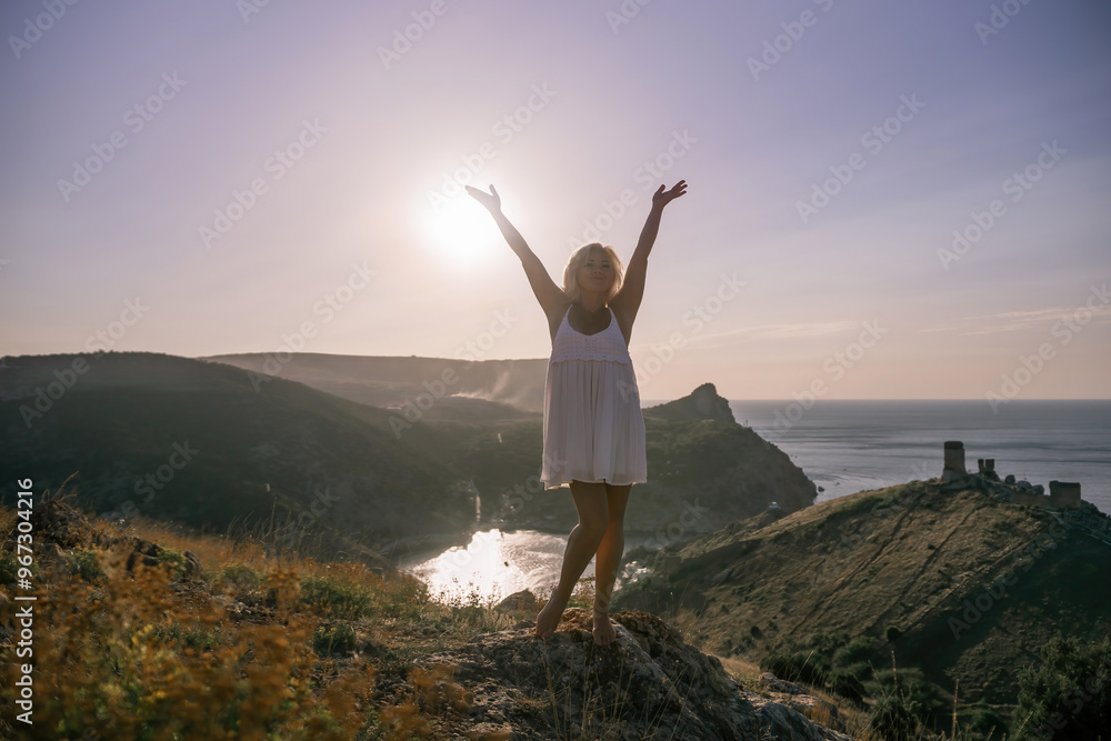 woman standing hill with her arms raised in the air, looking up at the sun. The scene is peaceful and serene, with the woman's expression conveying a sense of joy and happiness. woman standing hill with her arms raised in the air, looking up at the sun. The scene is peaceful and serene, with the woman's expression conveying a sense of joy and happiness.