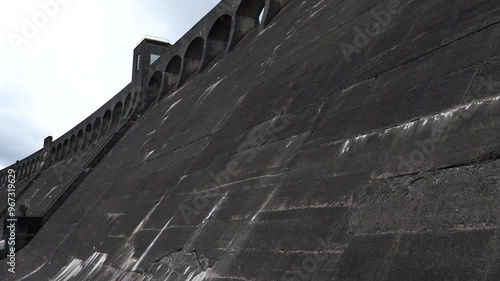 Downstream slope of Clatteringshaws Dam in Galloway Forest Park in summer, Scotland tilt down shot.
 photo