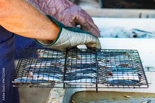 Male hands with gloves preparing sardines in a grill at 2024 