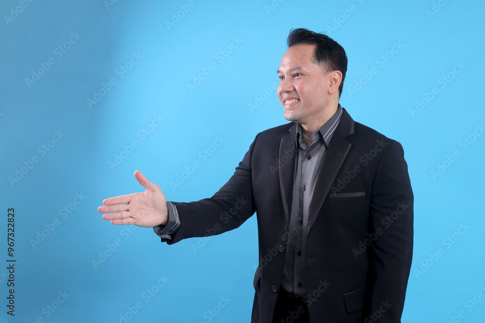 Male businessman in a suit stretching hand and shows a palm up gesture on a blue background. Concept of request and handshake. Male businessman in a suit stretching hand and shows a palm up gesture on a blue background. Concept of request and handshake.