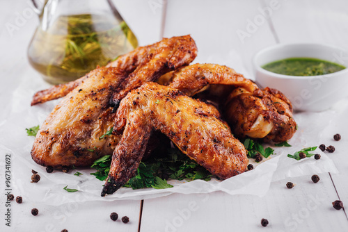 Delicious roasted chicken wings lying on white paper on white table photo