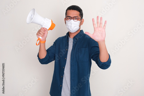 A man wearing medical face mask holding megaphone and showing five fingers sign photo