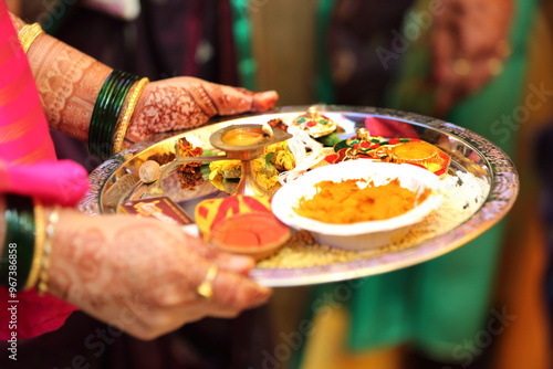 Indian pooja thali is a decorated plate used for rituals, containing a diya, incense sticks, kumkum, haldi, rice, flowers. It is essential for offering prayers to deities during religious ceremony. photo